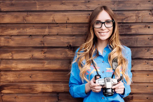 Feliz jovem hipster mulher em óculos detém retro foto câmera Fotografia De Stock