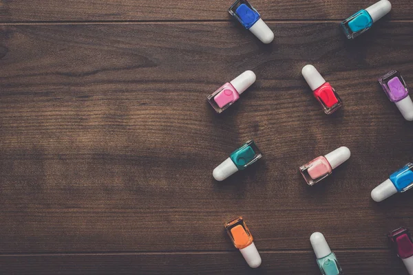 Nail polish bottles on brown wooden table — Stock Photo, Image