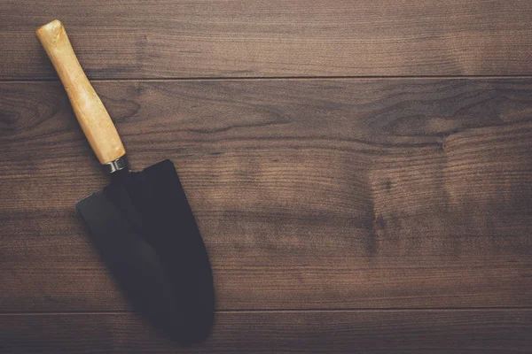 Zwarte tuinieren schop op de houten tafel — Stockfoto