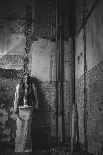 Zombie girl med loong hår i en övergiven byggnad håller kni — Stockfoto