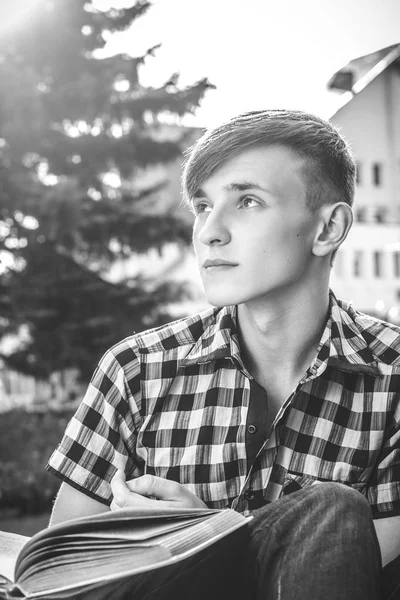 Man sitting on bench in park and readindg book — Stock Photo, Image