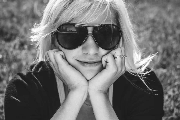 Young girl in sunglasses sitting on grass — Stock Photo, Image