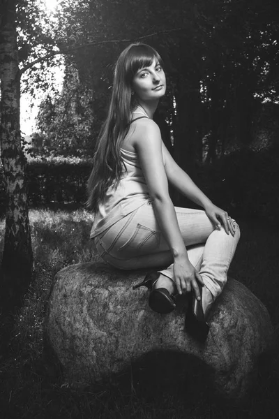 Girl sitting on the big stone in park — Stock Photo, Image