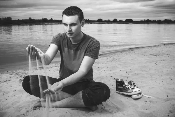 Thoughtful young man sitting on the beach — Stock Photo, Image