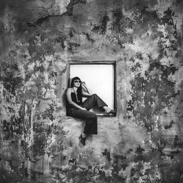 Girl sitting on window of abandoned building — Stock Photo, Image