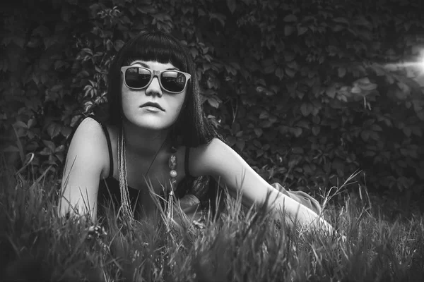 Menina vestindo óculos de sol sobre folhagem fundo — Fotografia de Stock