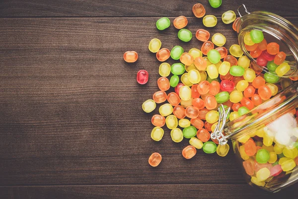 Gekanteld glazen pot vol met kleurrijke snoep — Stockfoto