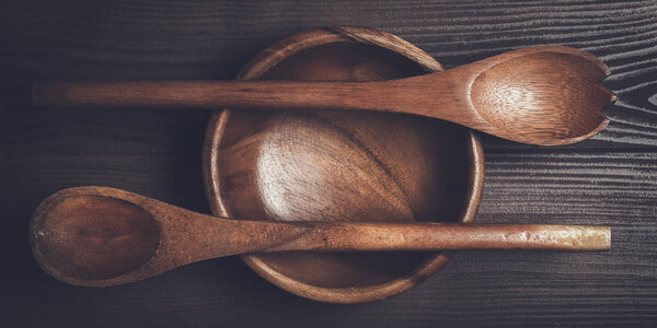 empty salad bowl and two spoons on wooden table