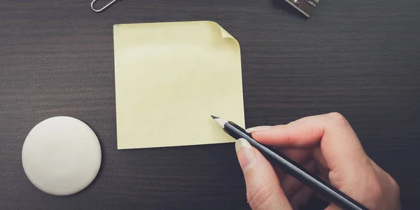 Женщина пишет карандашом на желтой наклейке — стоковое фото