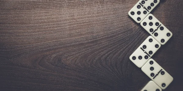 Domino kusů tvořících cik cak přes dřevěný stůl — Stock fotografie