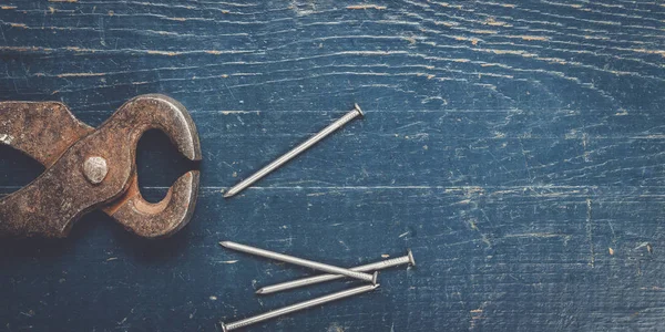 Old rusty tongs on blue table — Stock Photo, Image