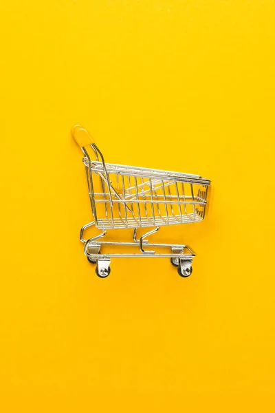 Sarı arka plan üzerinde alışveriş arabası — Stok fotoğraf