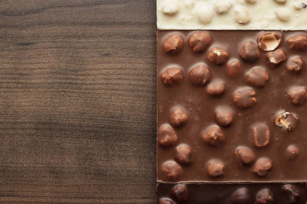 Different chocolate bars with whole hazelnuts — Stock Photo, Image