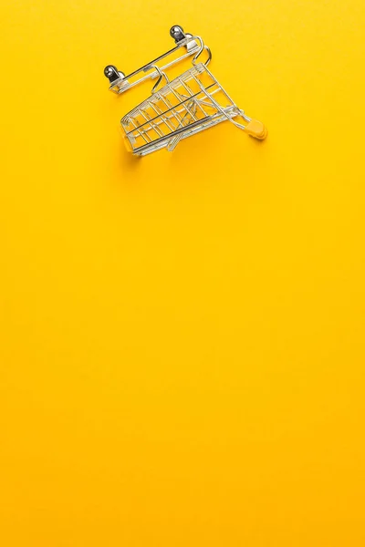 Wózek na zakupy na żółtym tle — Zdjęcie stockowe