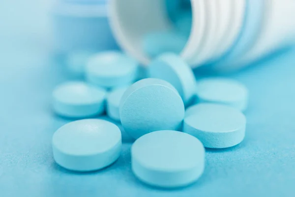 Převržený plastová nádoba s modré pilulky — Stock fotografie