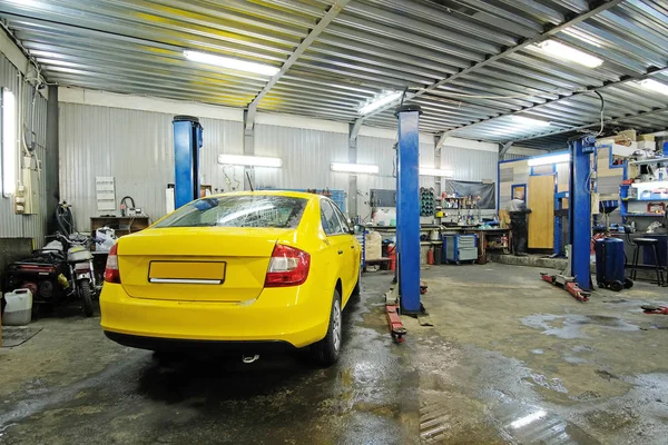 Táxi amarelo em reparação em uma estação de reparo de carro — Fotografia de Stock