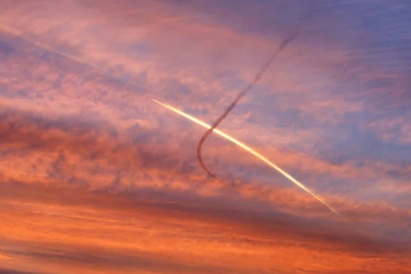 与交叉的平面痕迹的夕阳的天空 — 图库照片