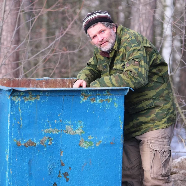 Бродяга возле мусорного бака — стоковое фото