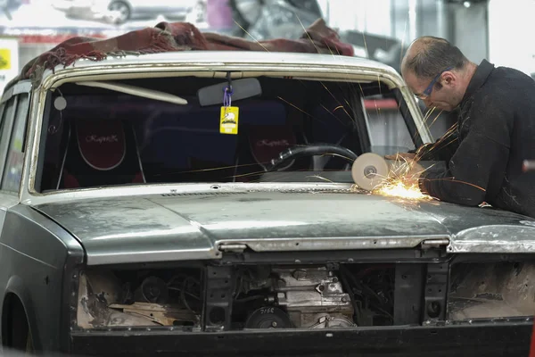 Працівник працює з кутовою шліфувальною машиною в майстерні по ремонту автомобілів — стокове фото