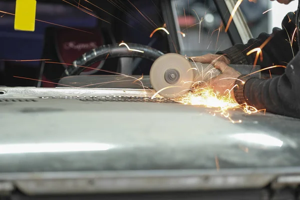 Worker works with angle grinder in a car repair shop — Stock Photo, Image