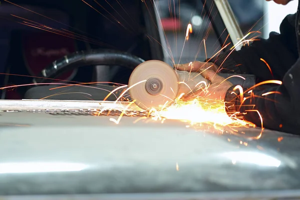 Trabajador trabaja con amoladora angular en un taller de reparación de automóviles — Foto de Stock