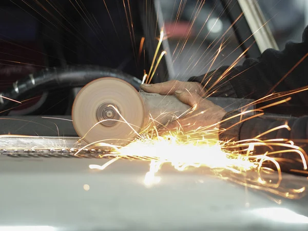 Travailleur travaille avec meuleuse d'angle dans un atelier de réparation automobile — Photo