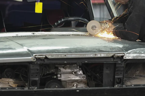 Trabajador trabaja con amoladora angular en un taller de reparación de automóviles —  Fotos de Stock