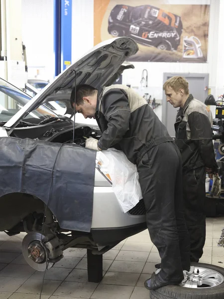 Travailleurs travaillent avec une voiture dans un poste de réparation automobile — Photo