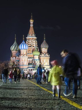 Moskova, Rusya - 28 Ekim 2019: Kızıl Meydan 'da gece boyunca St. Mary' nin arka planında yürüyen turist görüntüsü Moskova 'daki Basil Katedrali