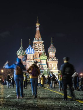 Moskova, Rusya - 28 Ekim 2019: Kızıl Meydan 'da gece boyunca St. Mary' nin arka planında yürüyen turist görüntüsü Moskova 'daki Basil Katedrali