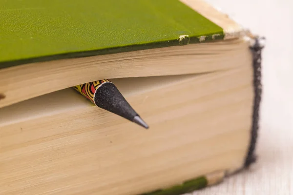 Close-up image of part of a closed book with a pencil instead of a bookmark