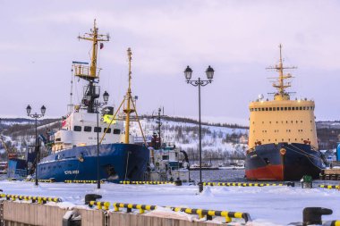 Murmansk, Rusya - 5 Ocak 2020: Kışın Murmansk şehrinde donmayan liman. Fotoğraf öğleden sonra 2 'de kutup gecesinin en yoğun saatinde çekilmiş.