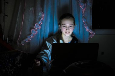 Gece evde dizüstü bilgisayarla oturan bir kızın görüntüsü
