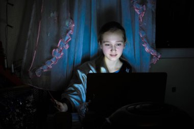Gece evde dizüstü bilgisayarla oturan bir kızın görüntüsü