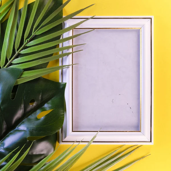 image of a photo frame on a yellow background framed by leaves