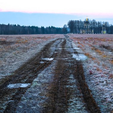 Kiliseye giden toprak yolu olan bir kış manzarası.