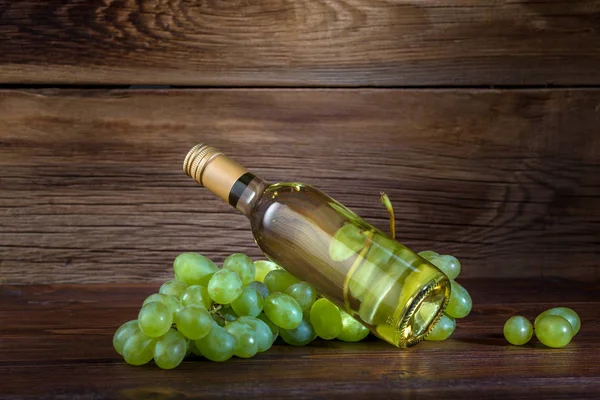 Una botella de vino blanco con uvas sobre fondo de madera —  Fotos de Stock