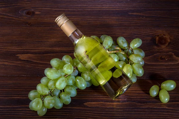 Una botella de vino blanco con uvas sobre fondo de madera —  Fotos de Stock