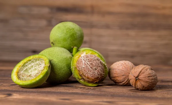 Ceviz ahşap arka plan üzerinde taze hasat. Yeşil ve kahverengi fındık. Kabuk ve ceviz kabuğu. Ceviz ahşap yüzeye