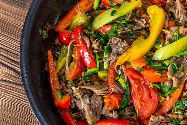 La carne con hortalizas en la sartén sobre el fondo de madera — Foto de Stock