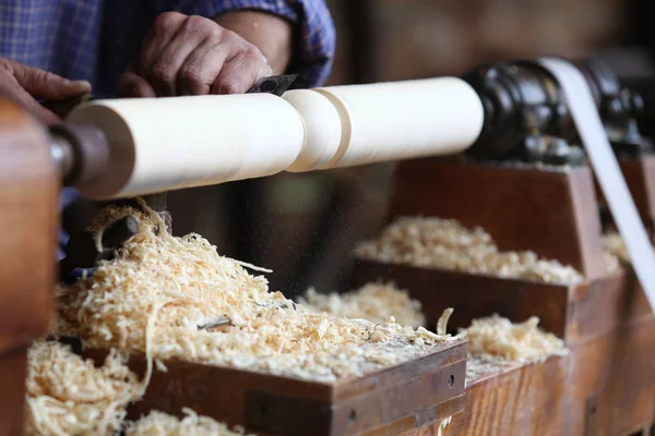 Man holds a chisel in his hand and makes a wooden product on a lathe in the workshop — Stock Photo, Image