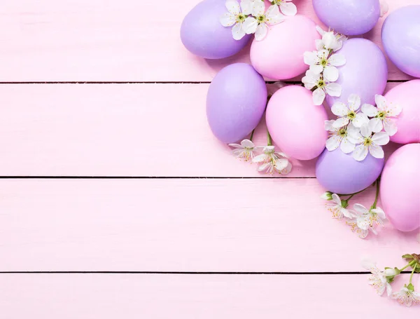 Ovos de Páscoa e flores brancas na mesa de madeira rosa . — Fotografia de Stock