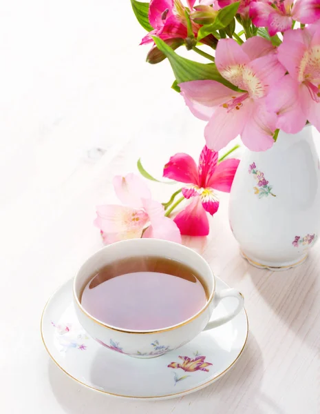 Ретро натюрморт с чашкой чая и цветами — стоковое фото