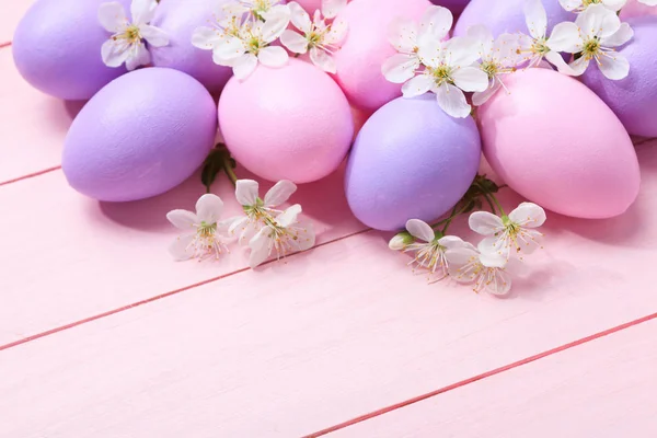 Oeufs de Pâques et fleurs blanches sur table en bois rose . — Photo