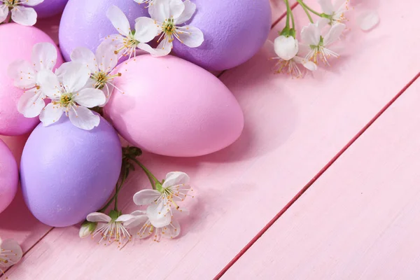 Ostereier und weiße Blumen auf rosa Holztisch. — Stockfoto