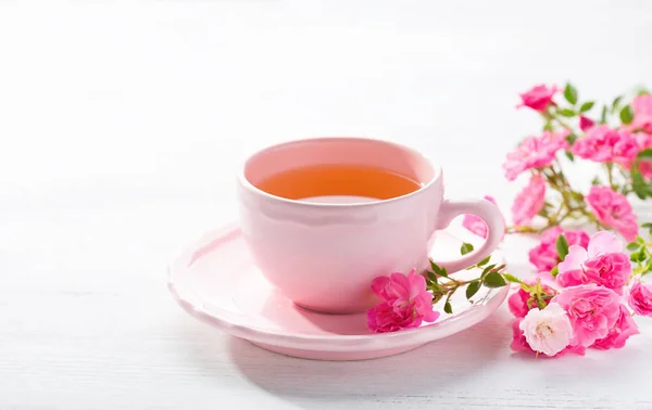 Tasse Tee und Zweig kleiner rosa Rosen. — Stockfoto