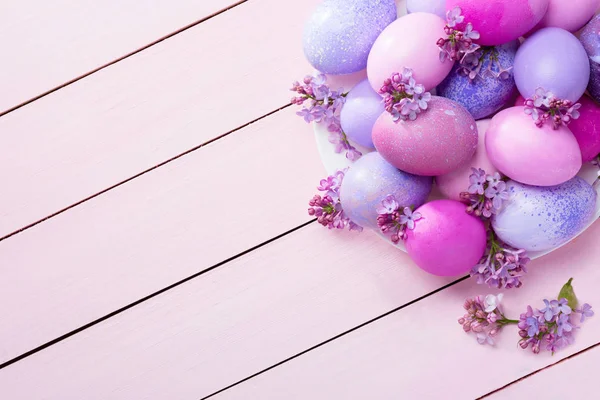 Paaseieren en lila bloemen (Syringa) op roze houten tafel. Rechtenvrije Stockfoto's