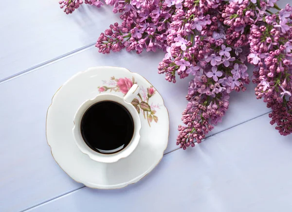 Fincan kahve ve ahşap masa üzerinde çiçek leylak dalı. — Stok fotoğraf