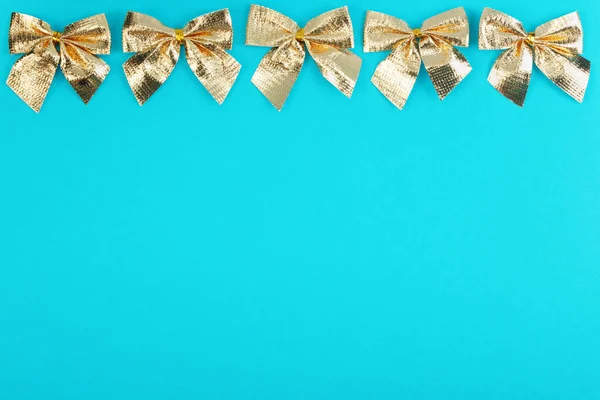 Gold christmas bows on blue background. — Stock Photo, Image