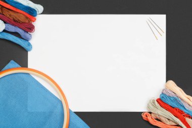Nakış işlemeli beyaz kağıt ve çok renkli dikiş iplikleri ve siyah arka planda dikiş..